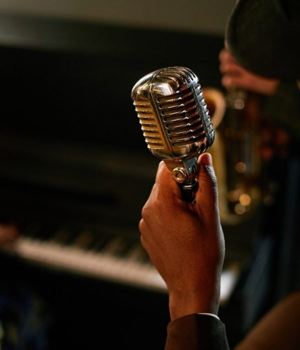 Male Singer Holding Retro Stage Mic while Performing Jazz with Band Indoors